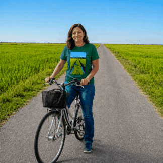 Dona amb bicicleta en una carretera entre arrossars del Delta de l’Ebre, amb samarreta verda estampada amb una foto d’un arrossar