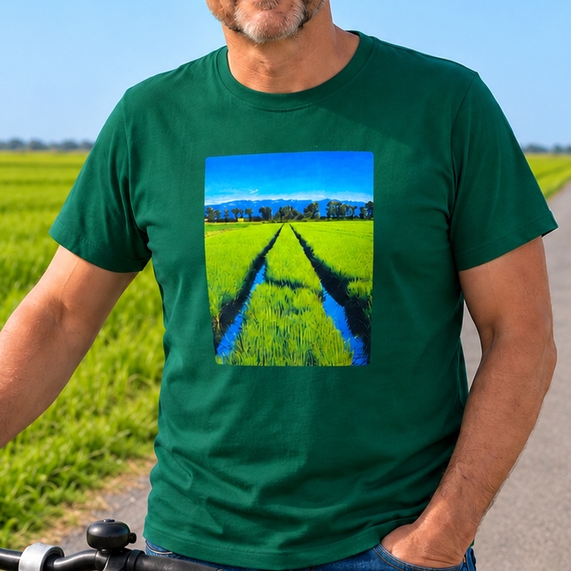 Home amb la samarreta verda Foto Arrossar de Lo Fang Club, mostrant l’estampat d’un arrossar amb canals d’aigua, al costat d’una bicicleta en un camí del Delta de l’Ebre.